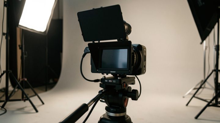 Caméra cinéma compacte installée sur un rig léger au sein d’un décor de tournage intérieur, avec écran orientable visible et éclairage de plateau réaliste.