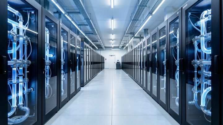 Salle française de calcul haute performance avec rangées de baies informatiques noires et système de refroidissement liquide visible, éclairée par une lumière froide.